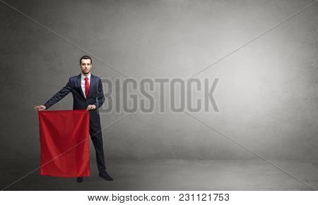 Businessman standing with red toreador cloth in his hand in an empty room