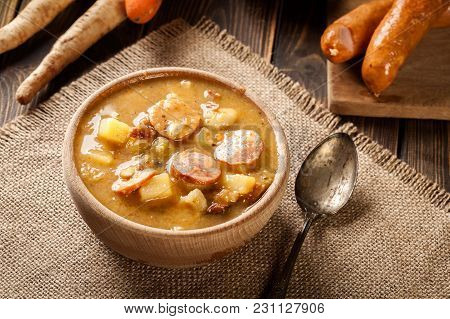 Wooden Bowl Of Split Pea Soup With Sausage And Potatoes