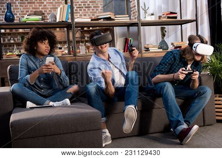 Friends Playing Video Game With Virtual Reality Headsets, African American Girl Sitting With Smartph