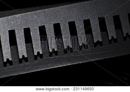 Closeup Of A Blade Of Thinning Scissors In The Dark Background.