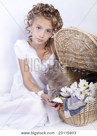 Una ragazza con i capelli ricci gioca con un gatto in un cestino
