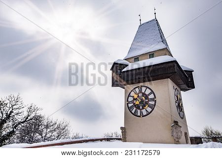 Sun Flares Over Snow Covered Uhrturm Clocktower Landmark Of City Graz On Hill Schlossberg In Winter