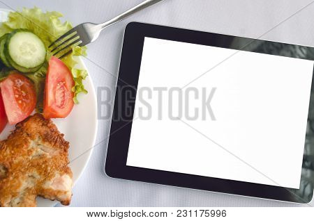 Tablet Computer With Blank Isolated Screen And Dish With Fresh Salad On The Restaurant Table Backgro