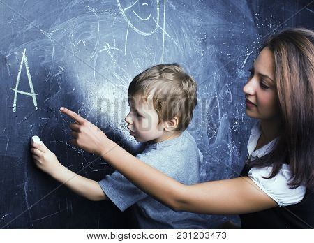 Little Cute Boy In Glasses With Young Real Teacher, Classroom Studying At Blackboard School Kido