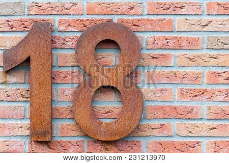 Rusted Number Eighteen In Red On A Brick Wall