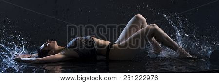 Sexy Brunette In Wet T-shirt Lying On The Floor Under Water In Dark Room Profile View