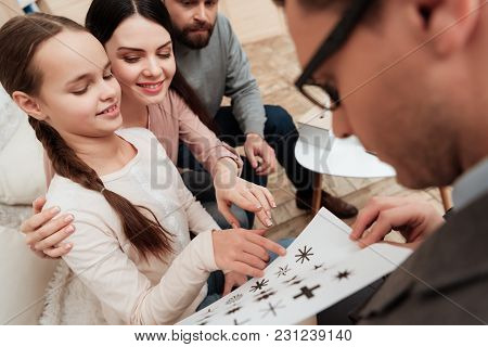 Little Girl With Her Parents Goes Through Logical Test With Psychologist, Choosing Figures On Sheet.
