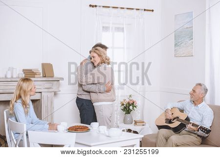 Elder Man Playing Guitar While Friends Spending Tme And Dancing In Room