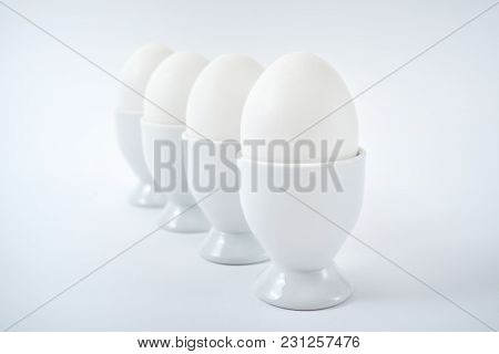White Eggs Standing On Egg Cup Isolated On White Background, Copy Space. Row Of Boiled Eggs In Stand