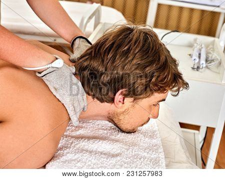 Body massage of silver threaded gloves at beauty salon. Electric stimulation skin care of man. Professional equipment for microcurrent lift. Methods of rejuvenation. Improvement of skin condition.