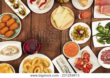 The Food Of Spain. An Overhead Photo Of Many Different Spanish Tapas, Shot From Above On A Dark Rust