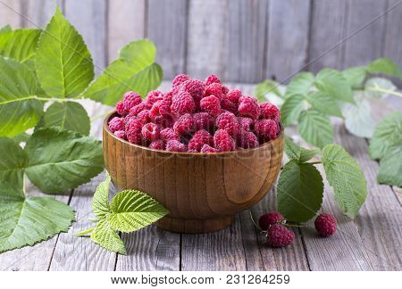 Red Fresh Raspberries On Brown Rustic Wood Background. Bowl With Natural Ripe Organic Berries With G