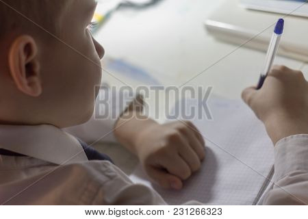 Close-up Of Boy Hand With Pencil Writing English Words By Hand On Traditional White Notepad Paper. B