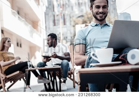 Positivity Is The Key To Success. Low Angle Shot Of A Millennial Guy Sitting In A Cafe And Smiling W