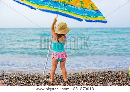 Child On The Beach Under An Umbrella