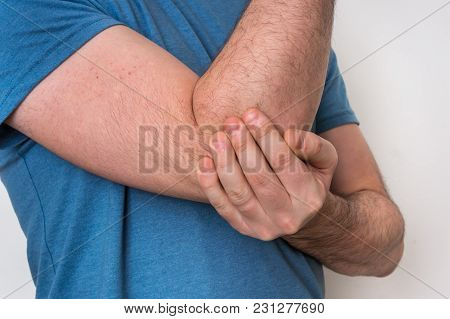 Man With Elbow Pain Is Holding His Aching Arm - Body Pain Concept