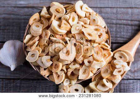 Bowl With Dried Garlic Flakes On Wooden Table