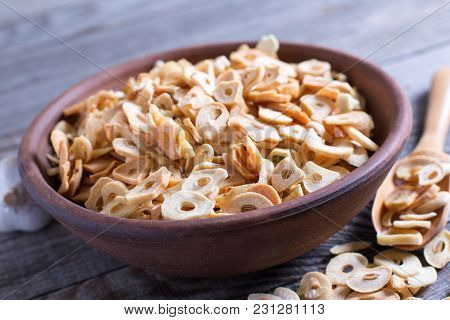 Bowl With Dried Garlic Flakes On Wooden Table