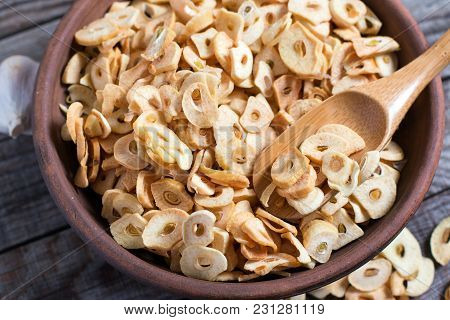 Bowl With Dried Garlic Flakes On Wooden Table