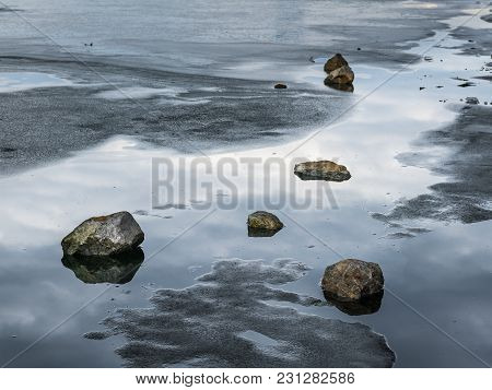 Stones Lying On The Melting Ice Of A Frozen River, Neue Donau Vienna Austria
