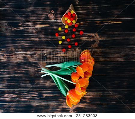 Tulips With Sweets In A Waffle Horn On A Wooden Background.