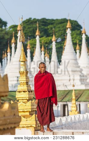 Mandalay, Myanma- December 13, 2015. Buddhist Young Monk Stands In Background Sandamuni Pagoda Stupa