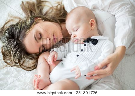 Mother And Her Baby Son, Sleeping On A Big Bed, Soft Back Light
