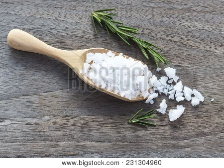 Sea Salt And Rosemary In A Wooden Spoon On The Table. Both Are Used For Seasoning, Enhance The Flavo