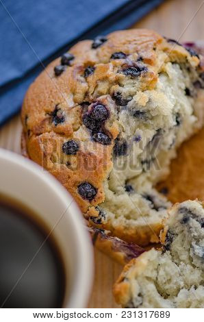 Broken Blueberry Muffing With A Cup Of Coffee And Blue Napkin