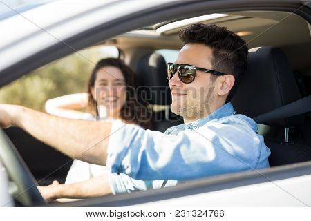 Good Looking Guy On Road Trip With Her Girlfriend. Man Driving A Car With Woman In The Passenger Sea