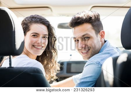 Rear View Of Beautiful Young Woman Sitting On Driving Seat Of Car With Her Partner Looking Back And 