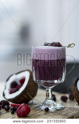 Lilac Cocktail With Berries And Coconut On A Wooden Table