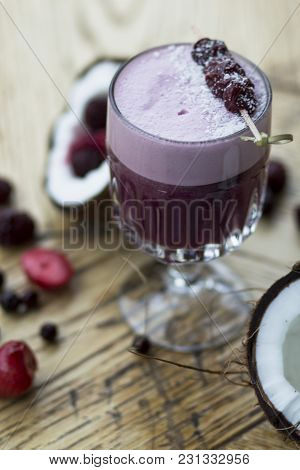 Lilac Cocktail With Berries And Coconut On A Wooden Table