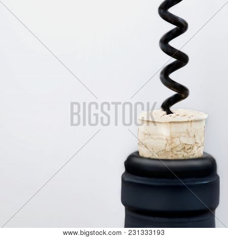Opening A Bottle Or Red Wine With Black Corkscrew Over Bright Grey Blurred Background With Copespace