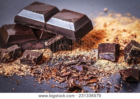 Chocolate. Pieces Of Dark Chocolate And Cacoa Powder On A Black Background Close-up. Chocolate Parts