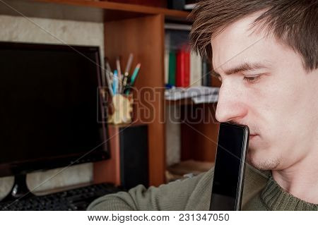 The Guy Sadly Looks Away, Closed The Rum With A Black Smartphone, In The Workplace