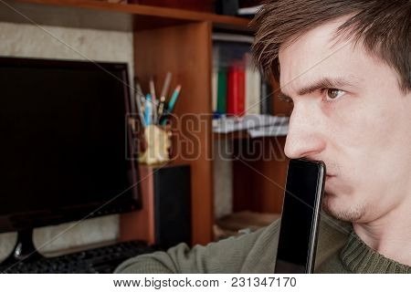 The Guy Suspiciously Looks Up, Closed The Rum With A Black Smartphone, In The Workplace