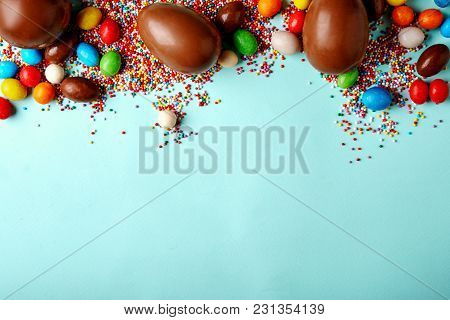 Easter Chocoalte Eggs And Sugar Multicolored Sprinkles On Blue Background With Copy Space. Top View