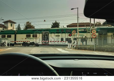 Driver Watches The Passage Of A Train Behind The Gates Of A Railroad Crossing