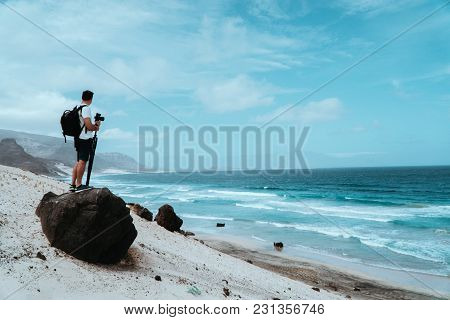 Traveler With Camera Staying On The Black Volcanic Boulder And Admiring Unusual Barren Landscape Of 