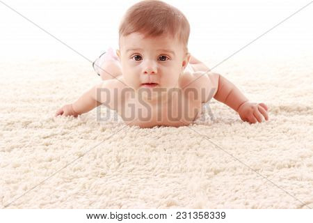 The Baby Is Lying On Her Stomach On The Carpet In The Room And Smiling On White Background