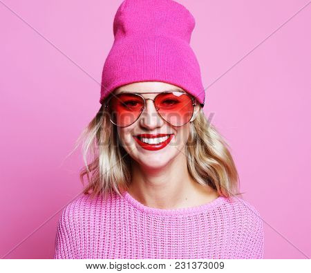 Stylish fashion portrait of trendy casual young woman in pink pulover and hat,