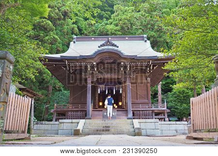 Asian Woman Praying In Front Of Main Hall Of  Goryo-jinja Shrine In Kamakura, Kanagawa Prefecture, J