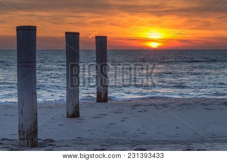 Wooden Piles On An Empty Beach And A Beautiful Sunset Sky Over The Sea, Petten, Holland,north Sea