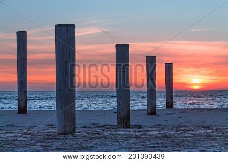 Wooden Piles On An Empty Beach And A Beautiful Sunset Sky Over The Sea, Petten, Holland,north Sea