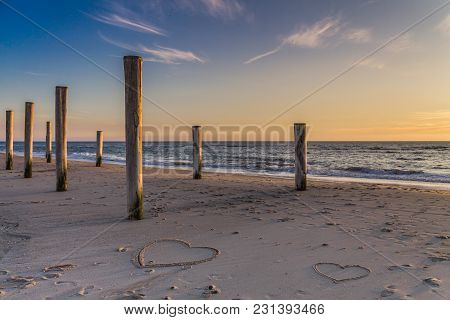 The Light Of Golden Hour At The Beach With Wooden Piles And Hearts Drawings In The Sand Petten, Holl