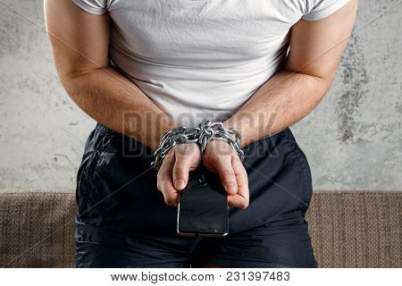 Close-up, The Man's Hand Is Tied With A Chain To The Smartphone. The Concept Is Dependent On Technol