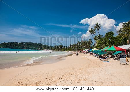 Mirissa Beach, Sri Lanka - JAN 2, 2017:  Tourists walking on the sand while enjoying the view across the wonderful beach of Mirissa on Jan 2, 2017. Sri Lanka.