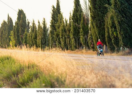 Running Super Mother With Child In Baby Stroller Enjoying Sunset And Mountains Landscape. Jogging Or