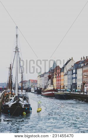 Copenhagen's Famous Nyhavn Harbour With The Typical Colorful Houses And Restaurants Along The Iced C
